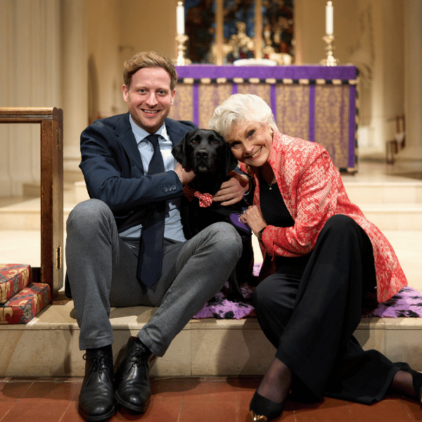 Photo of Nicholas Ralph and Angela Rippon stroking dog ambassador Daisy at an event