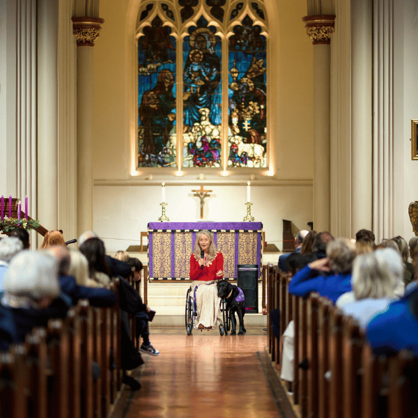 Photo of lady giving talk lady sat in wheelchair with assistance dog next to her