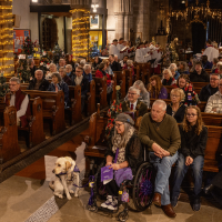 Church congregation with everyone sat in the pews. A canine partner can be seen at the front of the seats.