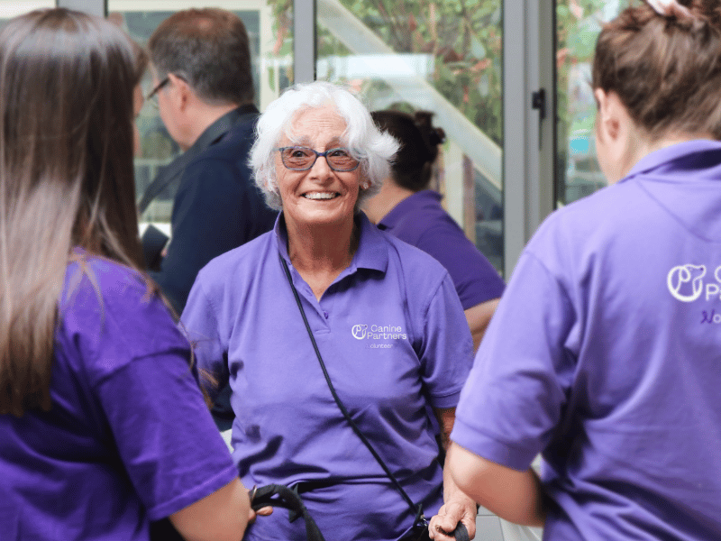 Photo of lady in purple Canine Partners top talking to other volunteers