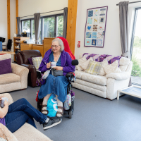 Partner sitting in a wheelchair speaking with a trainer in the National Training Centre lounge