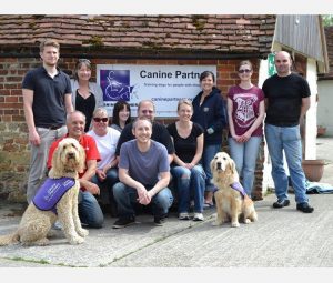 Group of corporate volunteers posing with two Canine Partners dogs