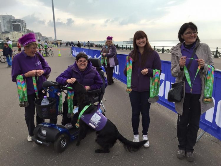 Canine Partners volunteers handing out medals at Bright10 racing event