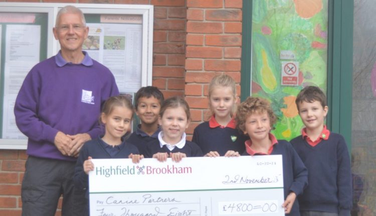 Brookham School students with Canine Partners volunteer holding giant cheque for £4,800