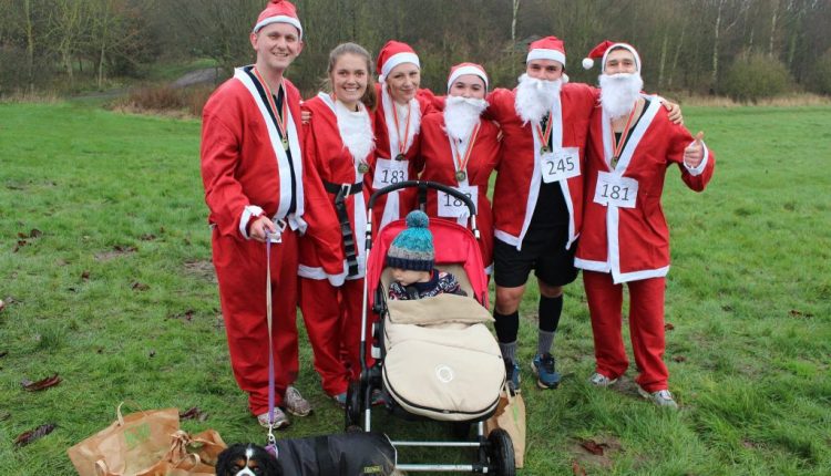 Group of fundraisers wearing in Santa Suits stood in field