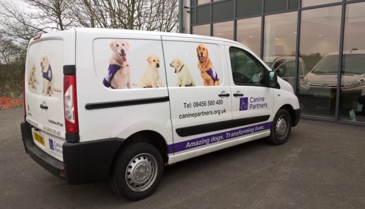 Canine Partners white van with dogs in purple jackets