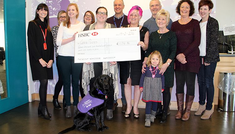 Giant cheque held by group of HSBC staff and family, presented to Canine Partners by HSBC in memory of a colleague.