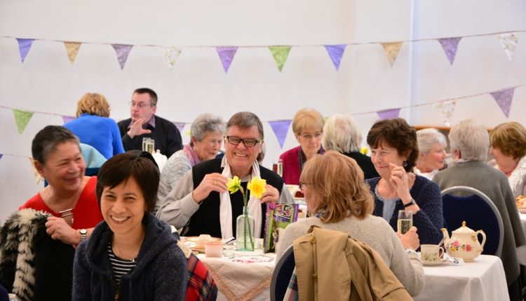 People sat at Midlands Cream tea event, with vintage crockery and bunting