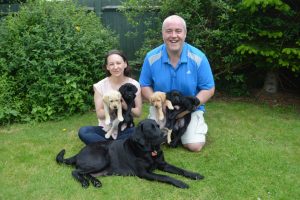 Wife and Husband volunteers for Canine Partners with brood bitch Pebble and her litter of puppies