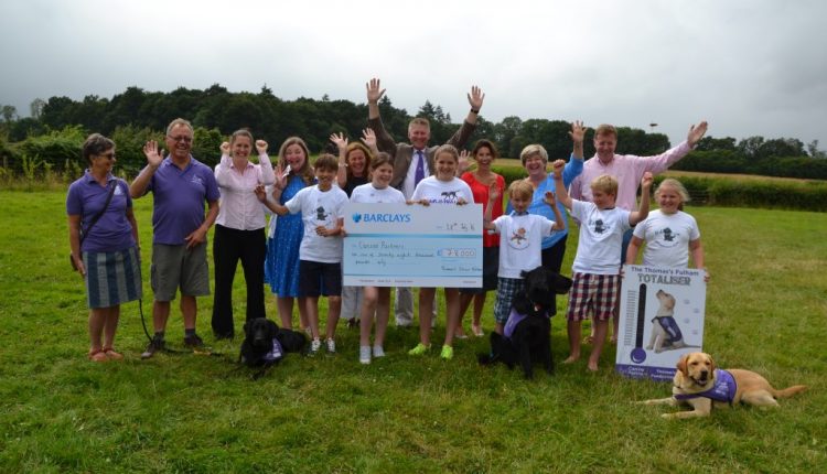 Group shot of Thomas's School Fulham students, canine partners dogs and volunteers holding giant cheque