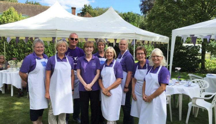 Group of volunteers in aprons getting ready to serve tea and cake at Afternoon Cream Tea event to raise funds