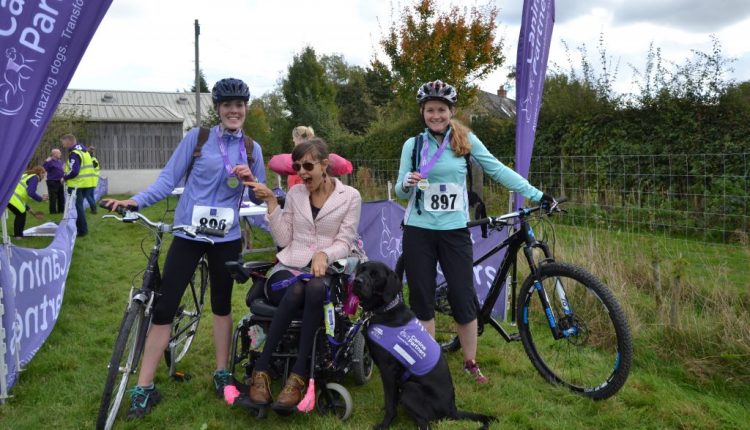 Canine Partners Advanced Trainer Claire Cannon and friend with partnership Sally and Ethan at cycling event finish line