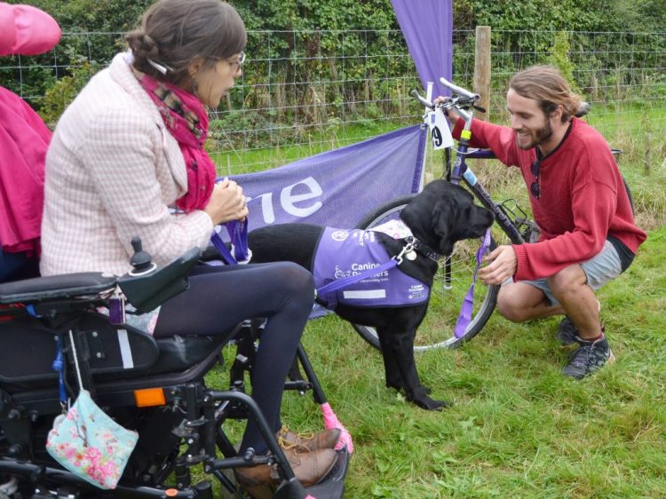 Sally and canine partner Ethan who is handing over medal to cyclist at Pedal for Paws cycling event