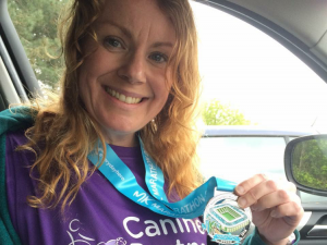 Canine Partners fundraiser Sam Foster holding Milton Keynes marathon medal