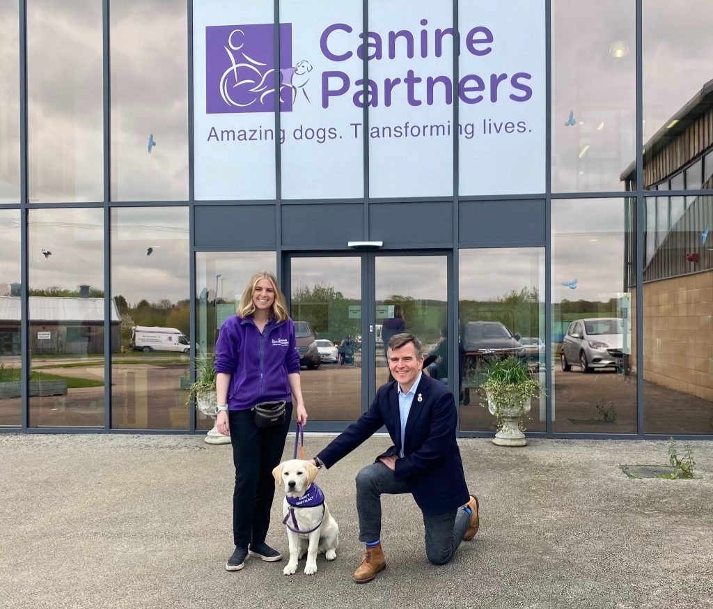 CEO, Alex, trainer and canine partner dog all standing together outside the Canine Partners building 